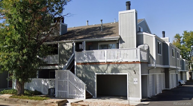 exterior space with fence, stairs, a balcony, a garage, and a chimney