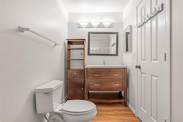 bathroom with toilet, vanity, and wood finished floors