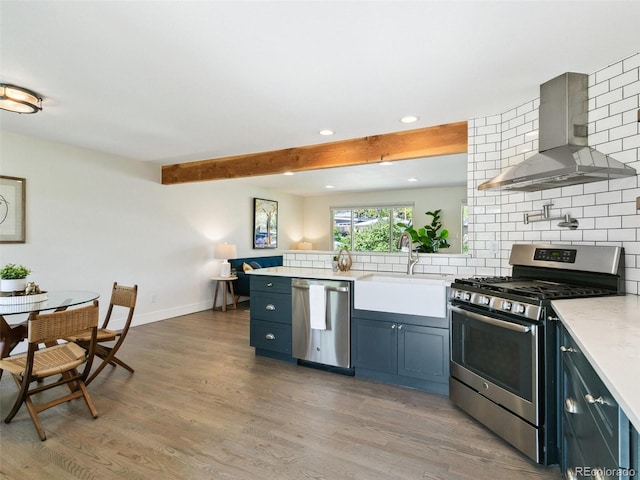 207 Iowa Dr, Golden, CO 80403 - kitchen with appliances with stainless steel finishes, wall chimney exhaust hood, a sink, recessed lighting, and decorative backsplash