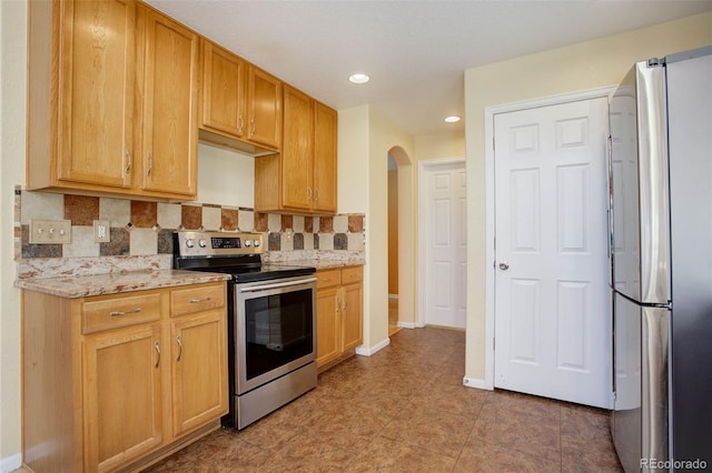 kitchen with light stone countertops, backsplash, and stainless steel appliances