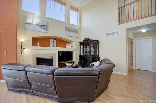 living room with crown molding, a towering ceiling, and hardwood / wood-style flooring