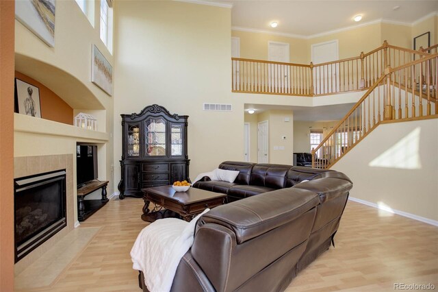 living room with plenty of natural light, light hardwood / wood-style floors, a fireplace, and a high ceiling