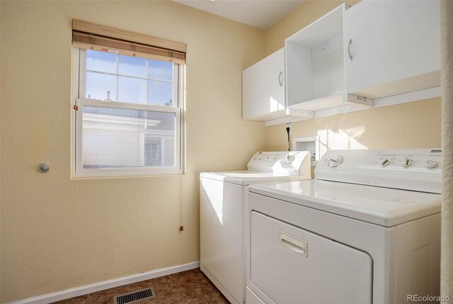 laundry area with dark tile patterned floors, cabinets, and separate washer and dryer