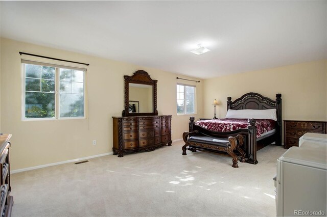 bedroom featuring light colored carpet and multiple windows