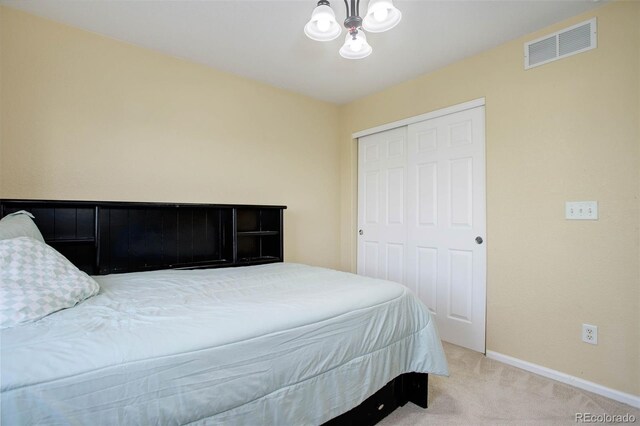 bedroom with carpet floors, an inviting chandelier, and a closet