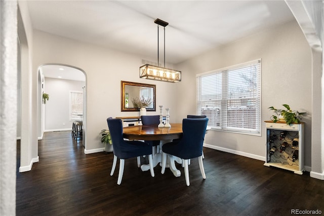 dining room with baseboards, arched walkways, and dark wood-style flooring