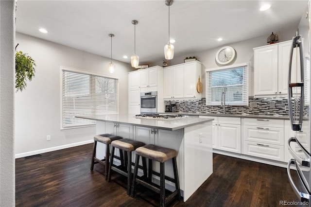 kitchen with stainless steel appliances, a center island, pendant lighting, and a sink