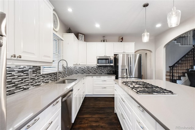 kitchen featuring stainless steel appliances, a sink, white cabinetry, light countertops, and pendant lighting