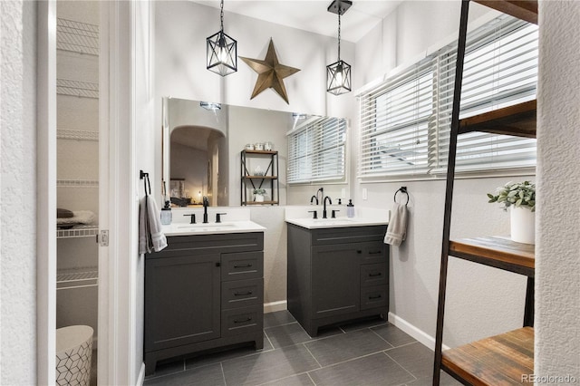 bathroom with tile patterned flooring, two vanities, a sink, and baseboards