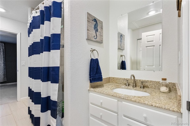 bathroom featuring a shower with shower curtain, vanity, and baseboards