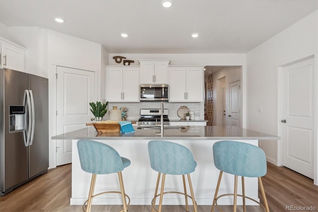 874 Ledge St, Lochbuie, CO 80603 - kitchen with appliances with stainless steel finishes, light wood-type flooring, decorative backsplash, a breakfast bar, and recessed lighting