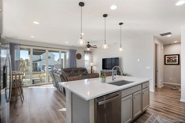 kitchen with gray cabinetry, sink, dishwasher, dark hardwood / wood-style floors, and an island with sink