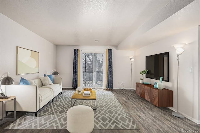 living room with a textured ceiling, baseboards, and wood finished floors