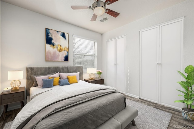 bedroom featuring a ceiling fan, visible vents, and wood finished floors