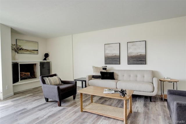 living area with light wood finished floors, a fireplace, and baseboards