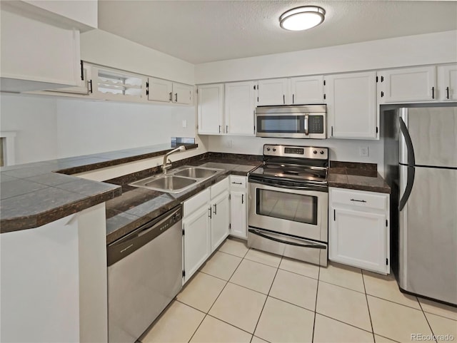12444 E Tennessee Cir Unit A, Aurora, CO 80012 - kitchen featuring appliances with stainless steel finishes, white cabinets, dark countertops, light tile patterned floors, and a textured ceiling