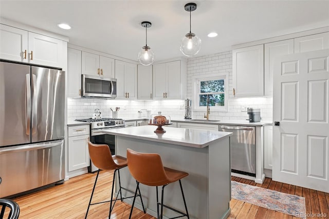 6830 Lamar St, Arvada, CO 80003 - kitchen featuring stainless steel appliances, a sink, a kitchen breakfast bar, decorative backsplash, and white cabinetry