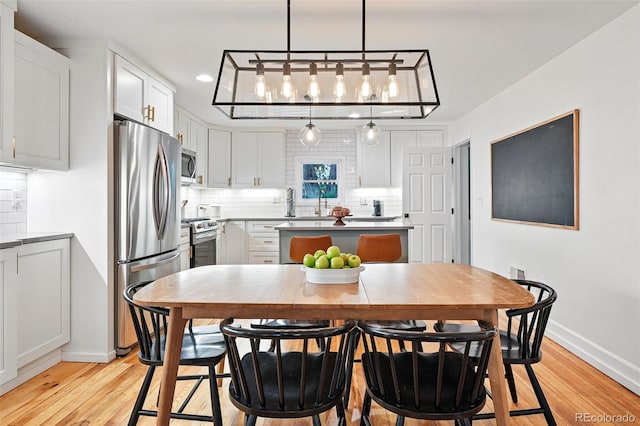 6830 Lamar St, Arvada, CO 80003 - dining area featuring light wood-style flooring, baseboards, recessed lighting, and a chandelier