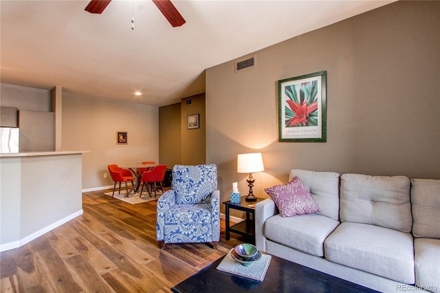 living area featuring a ceiling fan, visible vents, baseboards, and wood finished floors