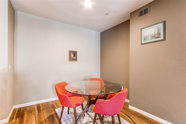 dining room featuring wood finished floors, visible vents, and baseboards