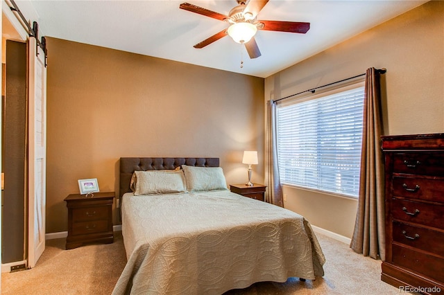 bedroom featuring light colored carpet, ceiling fan, baseboards, and a barn door