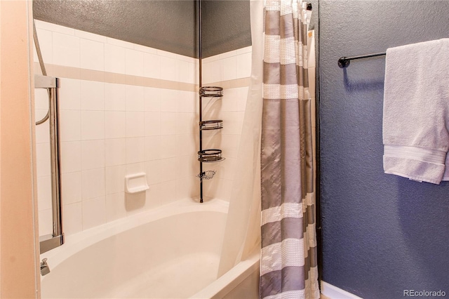 full bathroom with a textured wall and shower / bathtub combination with curtain