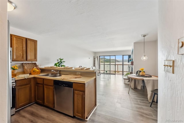 311 W La Bonte St Unit 306, Dillon, CO 80435 - kitchen with stainless steel dishwasher, a peninsula, a sink, brown cabinets, and wood finished floors