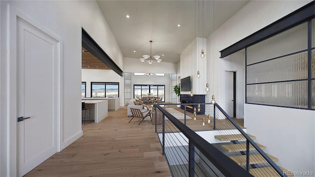 hallway featuring an inviting chandelier, high vaulted ceiling, and light wood-type flooring