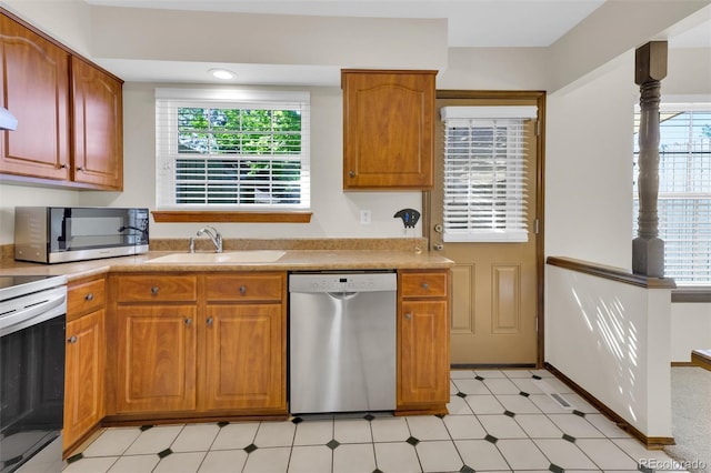 kitchen with appliances with stainless steel finishes, a sink, light countertops, and plenty of natural light