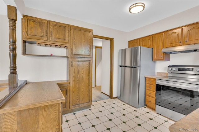 kitchen with appliances with stainless steel finishes, under cabinet range hood, light floors, and brown cabinets