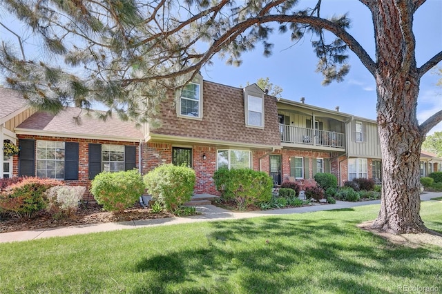 view of front of house featuring brick siding, a shingled roof, and a front lawn