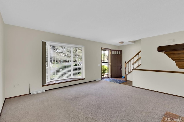 carpeted foyer entrance featuring stairway and baseboards