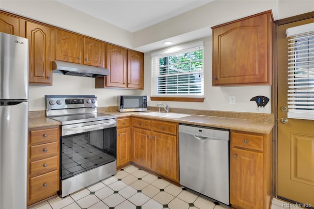 kitchen featuring stainless steel appliances, under cabinet range hood, light countertops, and light floors