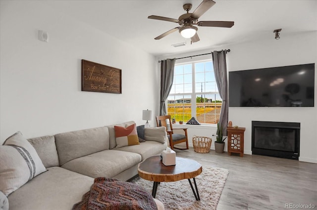 9227 Rolling Way Unit 201, Parker, CO 80134 - living area featuring wood finished floors, ceiling fan, and a glass covered fireplace