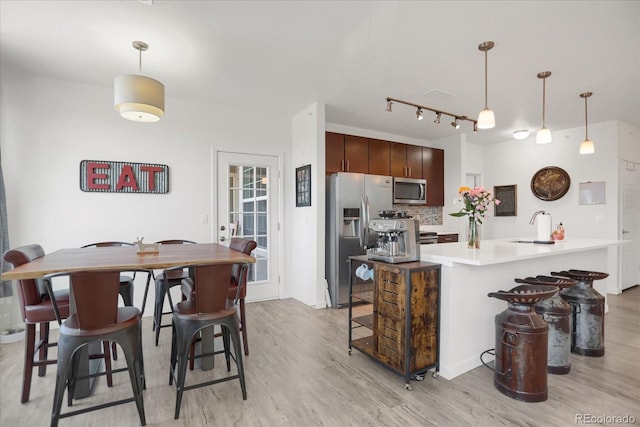 9227 Rolling Way Unit 201, Parker, CO 80134 - kitchen with appliances with stainless steel finishes, light wood-type flooring, a sink, a breakfast bar, and light countertops