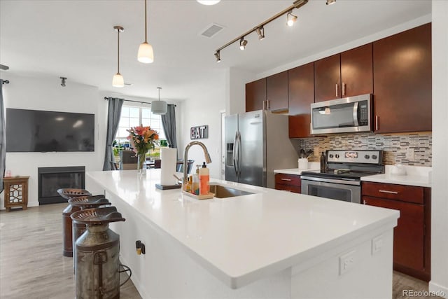 9227 Rolling Way Unit 201, Parker, CO 80134 - kitchen featuring stainless steel appliances, a sink, decorative backsplash, light countertops, and a kitchen island with sink