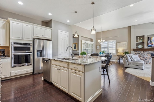 kitchen with a kitchen breakfast bar, light stone counters, stainless steel appliances, sink, and an island with sink