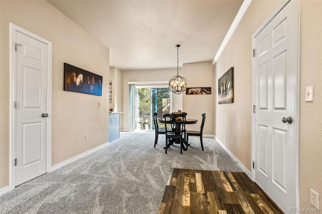 dining room featuring a textured ceiling, dark carpet, crown molding, and a chandelier