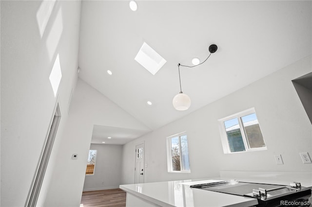 kitchen with pendant lighting, hardwood / wood-style floors, a skylight, and high vaulted ceiling