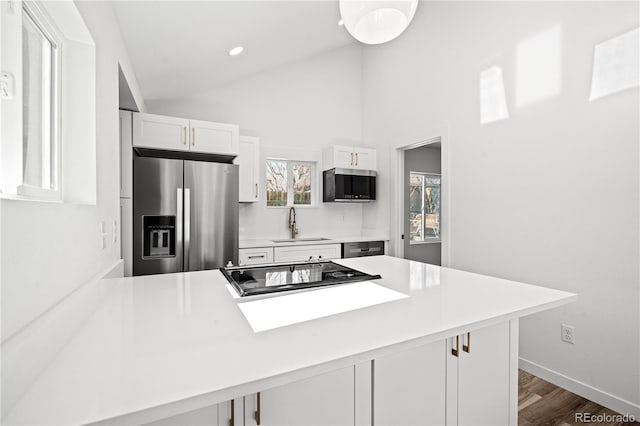 kitchen with a breakfast bar, stainless steel fridge with ice dispenser, white cabinetry, lofted ceiling, and kitchen peninsula