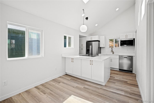 kitchen featuring white cabinetry, kitchen peninsula, pendant lighting, stainless steel appliances, and light hardwood / wood-style floors