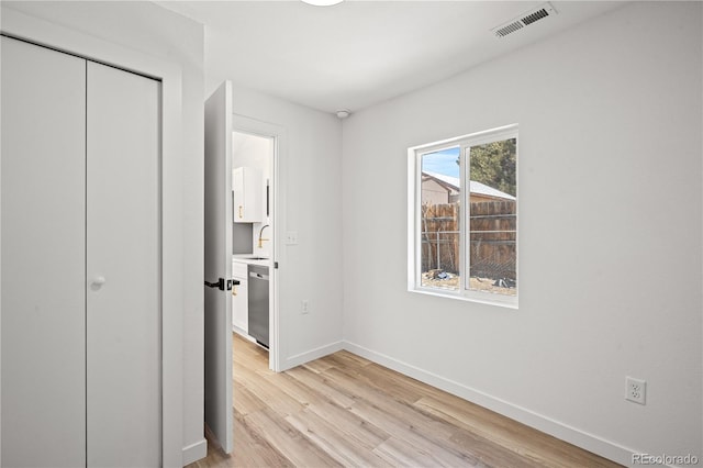 unfurnished bedroom featuring sink, light hardwood / wood-style floors, and a closet