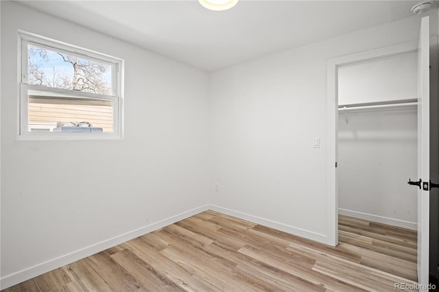 unfurnished bedroom with a spacious closet, light hardwood / wood-style floors, and a closet