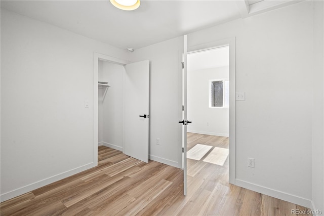 bedroom featuring a walk in closet, light wood-type flooring, and a closet