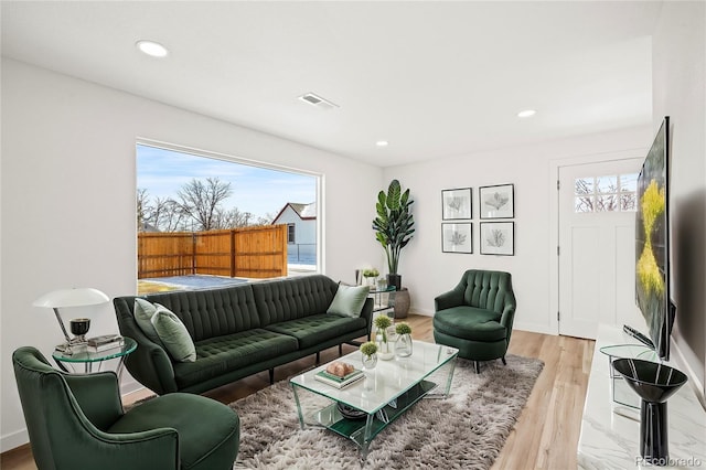 living room with recessed lighting, visible vents, light wood-style flooring, and baseboards