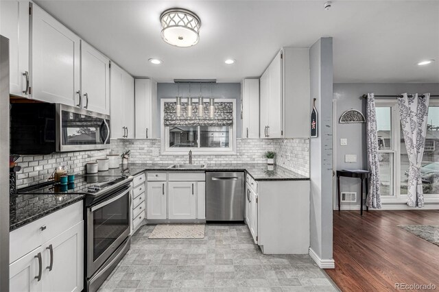 10478 Ogden St, Northglenn, CO 80233 - kitchen featuring stainless steel appliances, a sink, dark stone counters, white cabinetry, and decorative backsplash