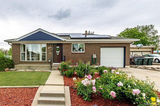 10478 Ogden St, Northglenn, CO 80233 - view of front of home with brick siding, a garage, driveway, solar panels, and a front lawn