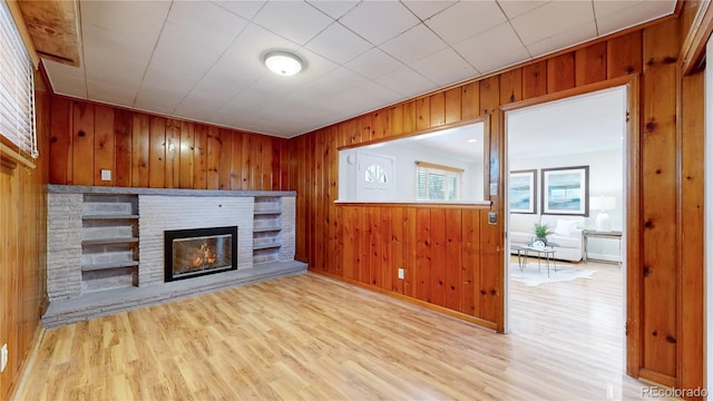 unfurnished living room with light hardwood / wood-style flooring and wood walls