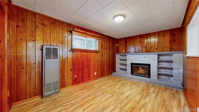 unfurnished living room with light wood-type flooring and wooden walls