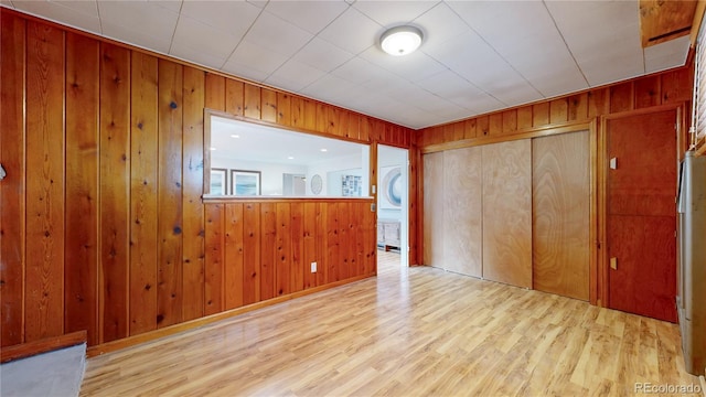 spare room featuring wood walls and light wood-type flooring